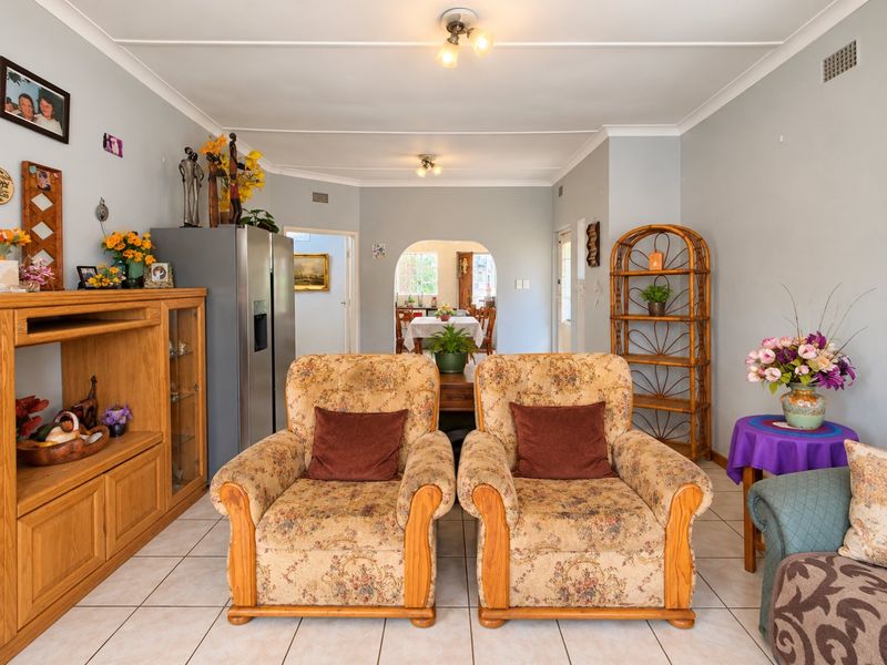 Open plan living area featuring tiled flooring and a central archway leading to the dining space, with neutral wall finishes throughout.