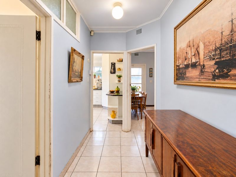 A bright, tiled hallway providing access to the kitchen and dining areas, featuring neutral wall tones and classic architectural details.