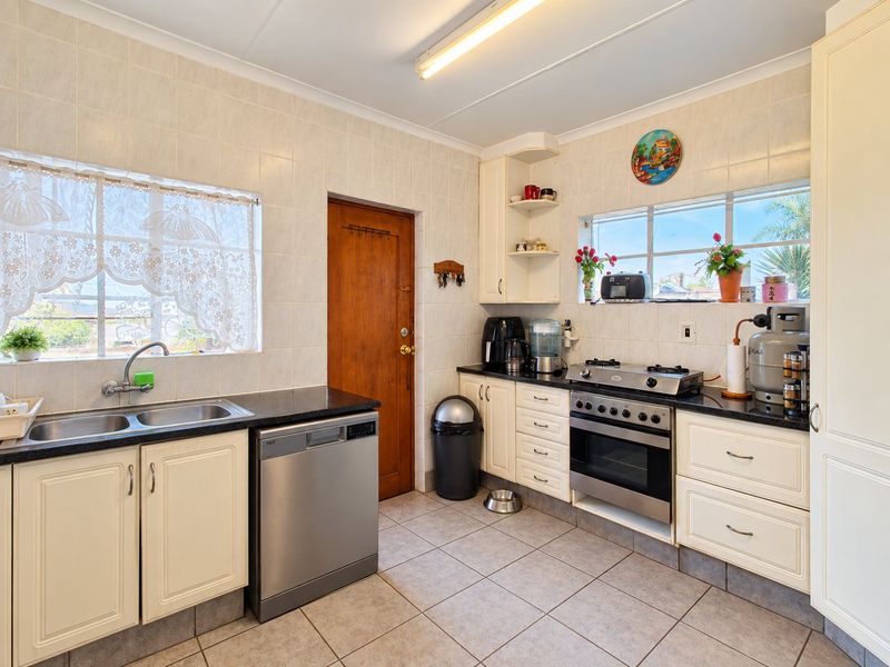A functional kitchen featuring tiled walls and flooring, built-in cabinetry, a double basin sink, and a gas stove with oven.