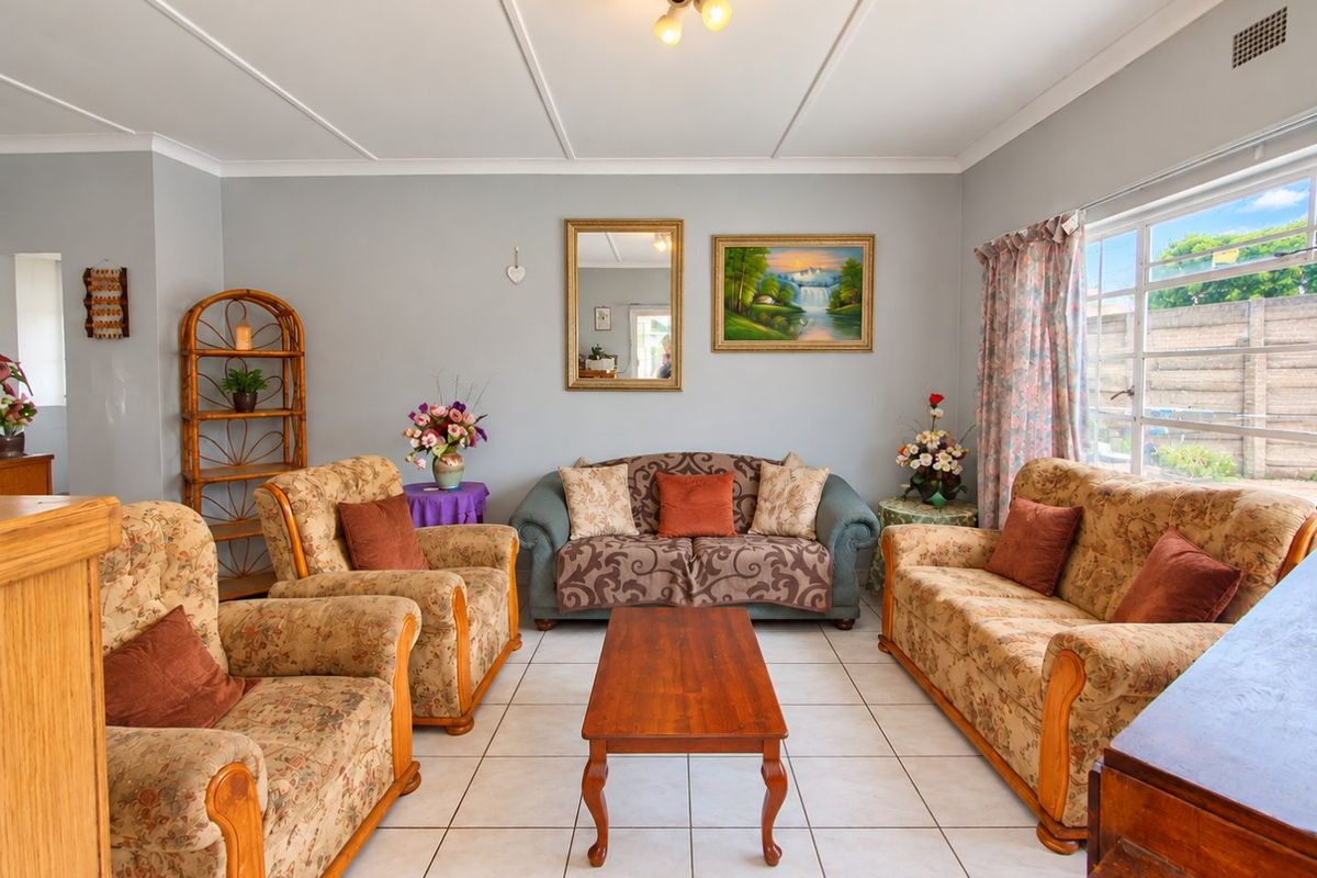 A well-lit living room featuring neutral tiled flooring, coved ceilings, and a large window providing natural light.