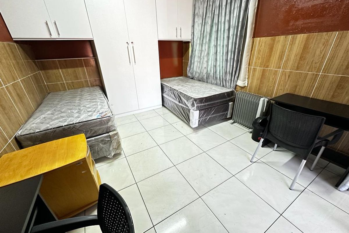 A bedroom featuring built-in cupboards, tiled flooring, and tiled wall accents, providing a functional space with integrated storage solutions.