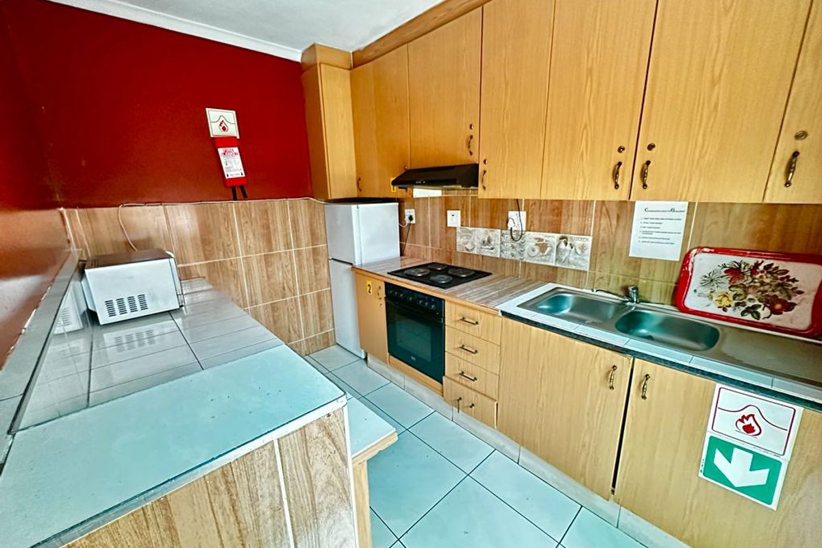 A functional kitchen featuring laminate cabinetry, tiled splashbacks, built-in oven with hob, and a double bowl stainless steel sink.