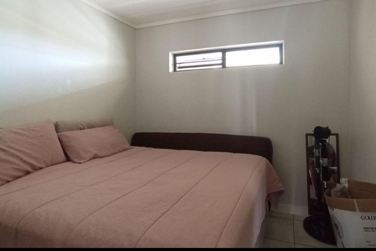 A compact bedroom featuring neutral wall finishes, tiled flooring, and a high-set horizontal window providing natural light.