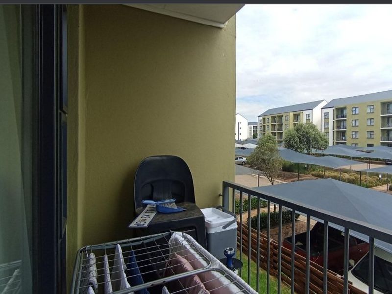 A functional apartment balcony featuring a metal balustrade and views over the complex parking area.