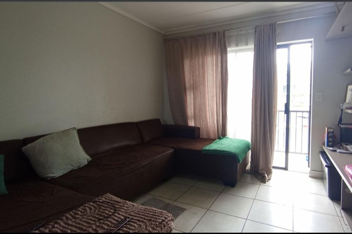 A living room featuring tiled flooring and a sliding glass door providing direct access to an outdoor balcony area.