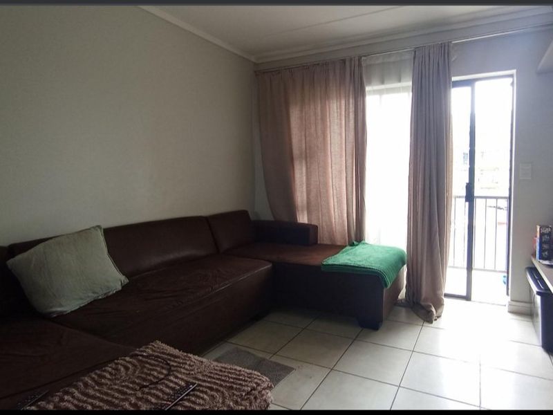 A living room featuring tiled flooring and a sliding glass door providing direct access to an outdoor balcony area.