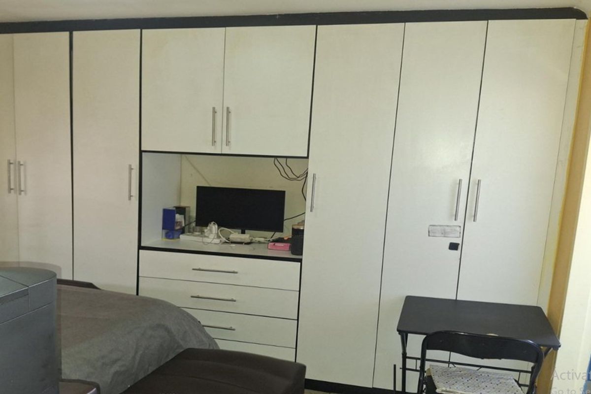 Bedroom featuring extensive white built-in cupboards with an integrated desk and drawer unit.