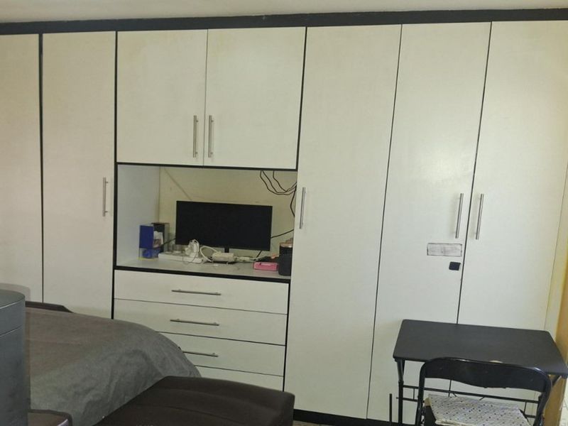 Bedroom featuring extensive white built-in cupboards with an integrated desk and drawer unit.