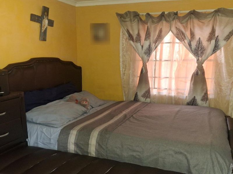 A functional bedroom featuring a built-in wardrobe and security burglar bars on the window.