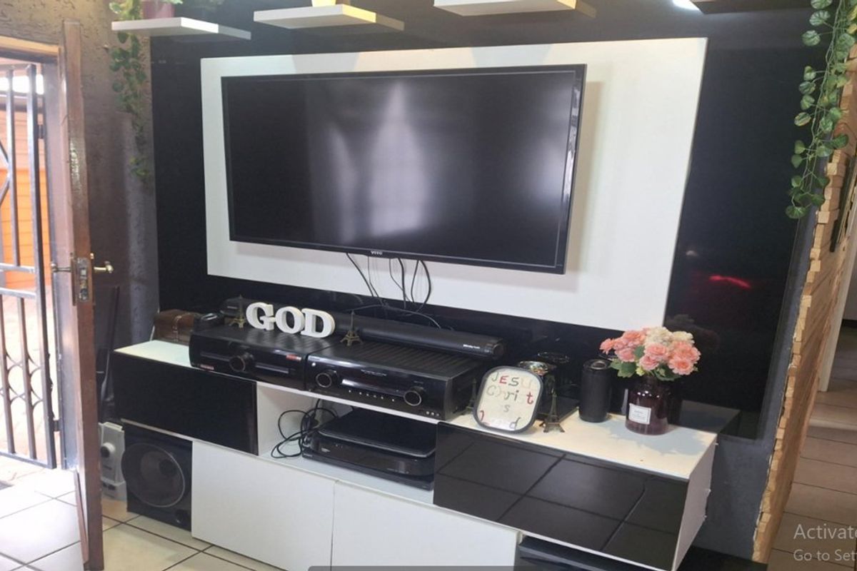 A living room area featuring a modern built-in media console with high-contrast black and white cabinetry and tiled flooring.