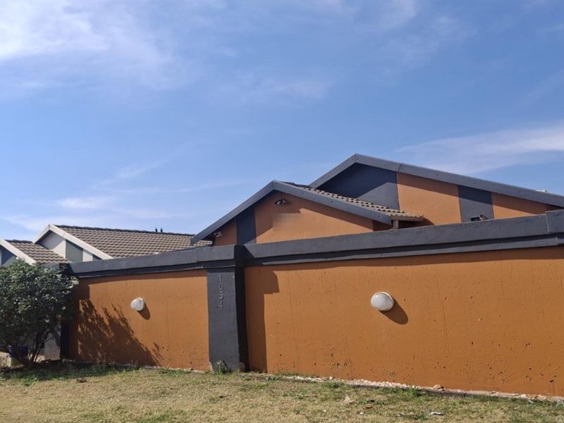 Front view of the property featuring a perimeter wall with exterior lighting and a tiled roof structure.