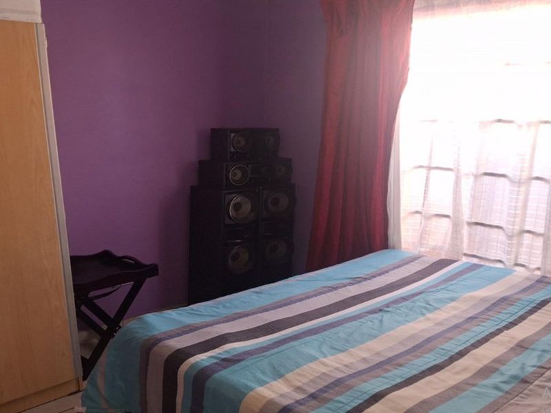 A bedroom featuring purple walls and a built-in wardrobe, providing functional storage space.