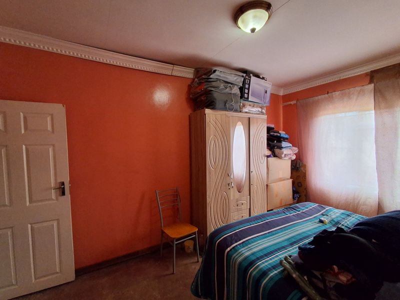 A bedroom featuring orange walls, ceiling cornice detailing, and a flush mount light fixture.