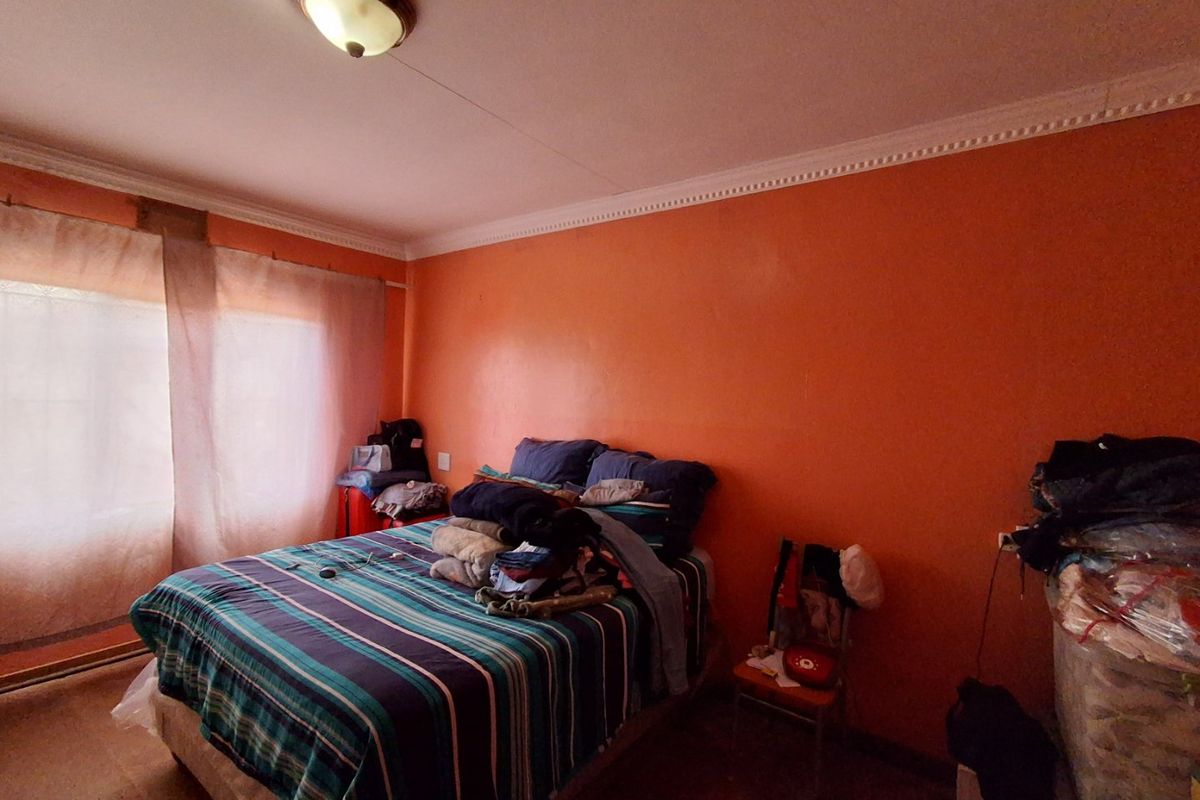A bedroom featuring orange painted walls, ceiling cornicing, and a central flush mount light fixture.