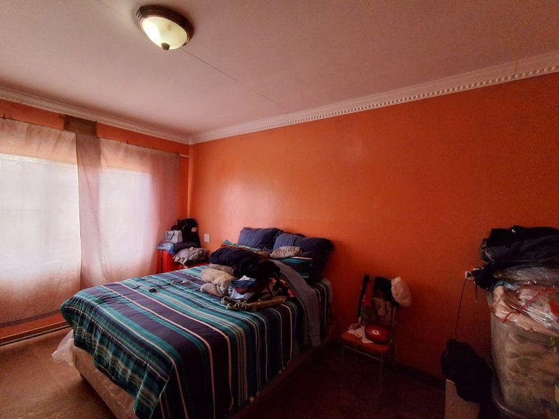 A bedroom featuring orange painted walls, ceiling cornicing, and a central flush mount light fixture.