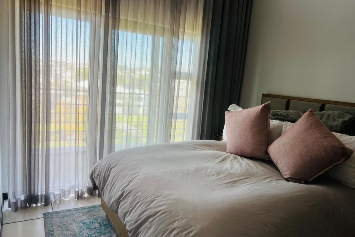 A well-lit bedroom featuring tiled flooring and large sliding glass doors that provide access to an outdoor balcony area.