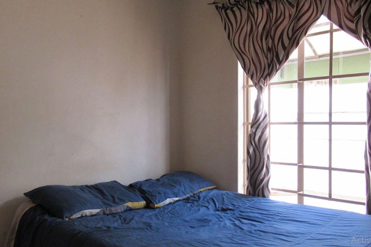 A bedroom featuring a window with installed security bars, providing natural light and basic security.