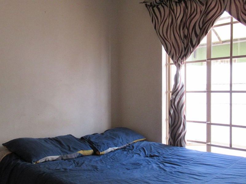 A bedroom featuring a window with installed security bars, providing natural light and basic security.