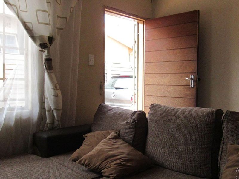 A living room area featuring a wooden door leading to the exterior and a window with security bars.