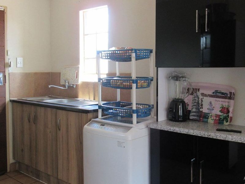A functional laundry area featuring built-in cabinetry, a stainless steel sink, and tiled flooring, providing practical utility space.