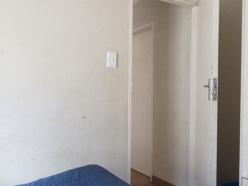 A view of a plain interior hallway with visible wear on the wall surfaces.