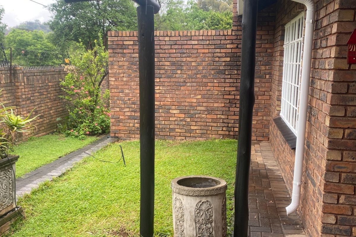 A private rear garden area featuring a brick boundary wall, paved pathways, and timber support posts, providing a secure outdoor space.