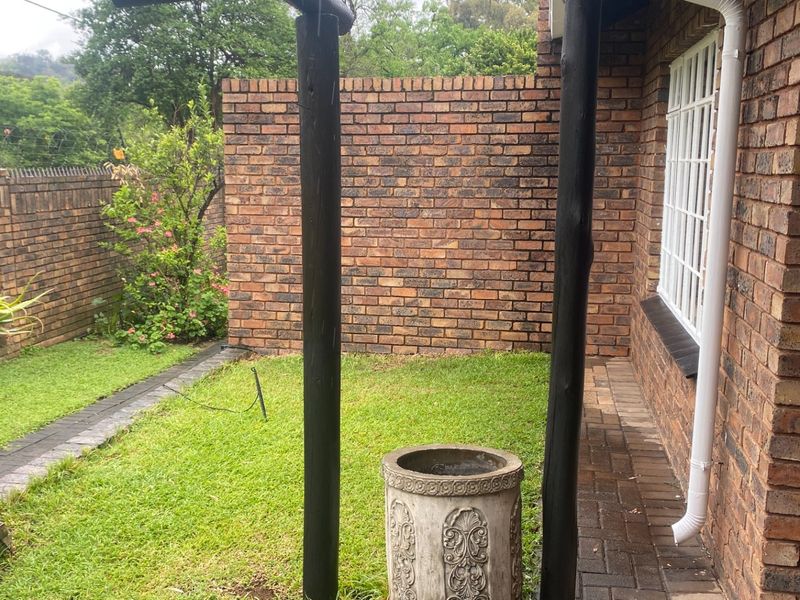 A private rear garden area featuring a brick boundary wall, paved pathways, and timber support posts, providing a secure outdoor space.