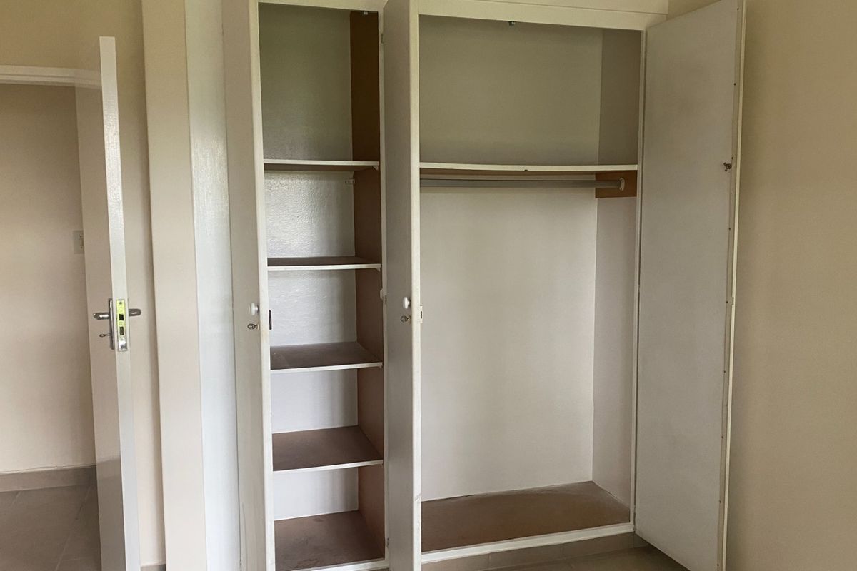 A bedroom featuring a functional built-in wardrobe with integrated shelving and a hanging rail, providing ample storage space.