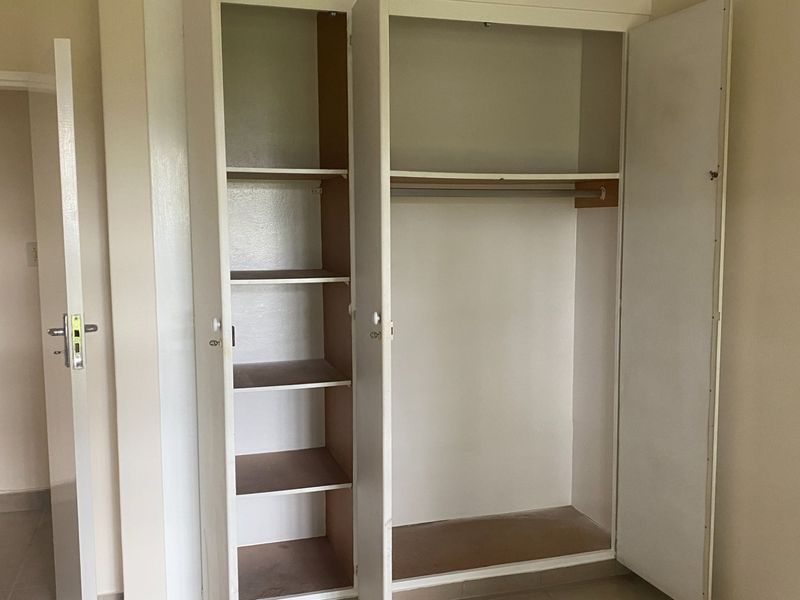 A bedroom featuring a functional built-in wardrobe with integrated shelving and a hanging rail, providing ample storage space.