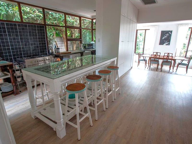 Spacious open-plan kitchen and dining area featuring a central island, extensive built-in cabinetry, and large windows overlooking the garden.