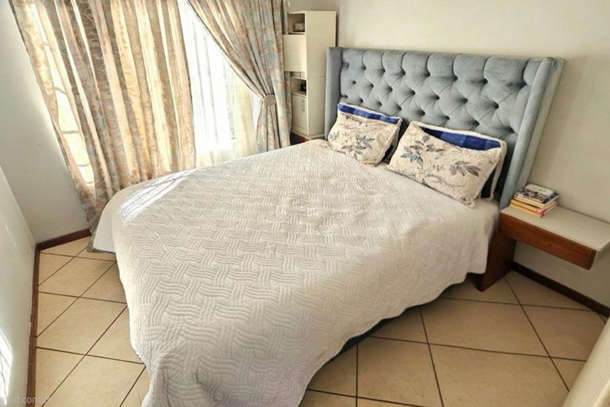 A well-lit bedroom featuring tiled flooring and a built-in bedside shelf, offering a functional and comfortable living space.