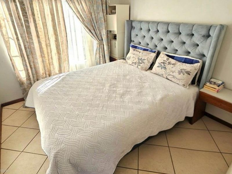 A well-lit bedroom featuring tiled flooring and a built-in bedside shelf, offering a functional and comfortable living space.