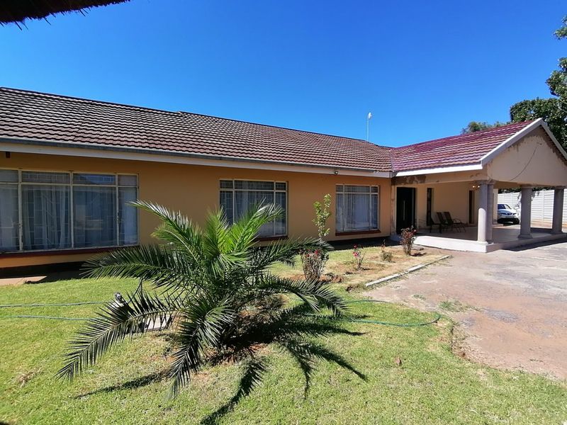 Front view of a single-story house featuring a tiled roof, covered entrance porch with concrete pillars, and a paved driveway.