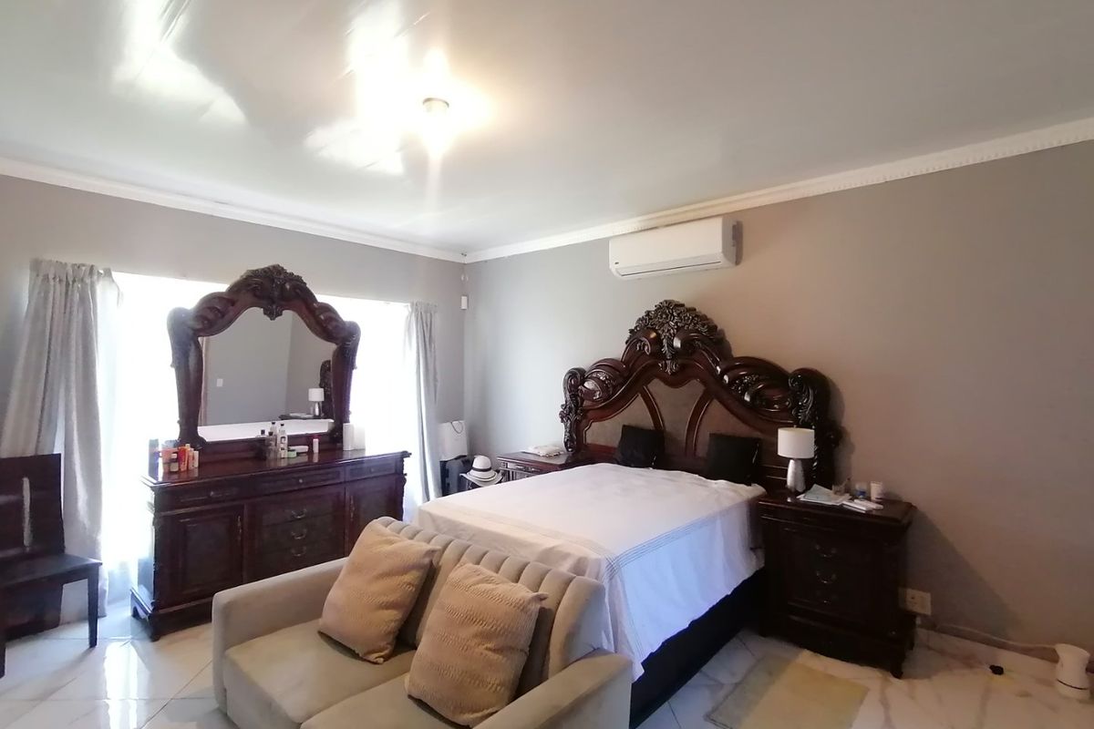 Spacious bedroom featuring tiled flooring, coving, and a wall-mounted air conditioning unit.