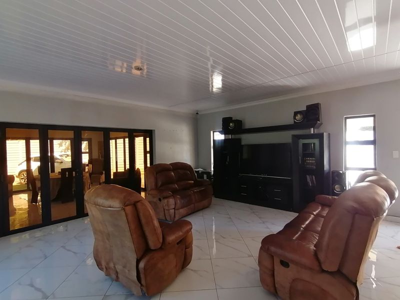 Spacious living room featuring large format tiled flooring, a modern PVC ceiling, and bi-fold doors providing access to the outdoor area.