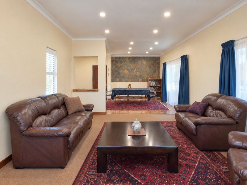 Spacious open-plan living and dining area featuring recessed downlighting, coved cornicing, and a decorative tiled feature wall in the dining section.