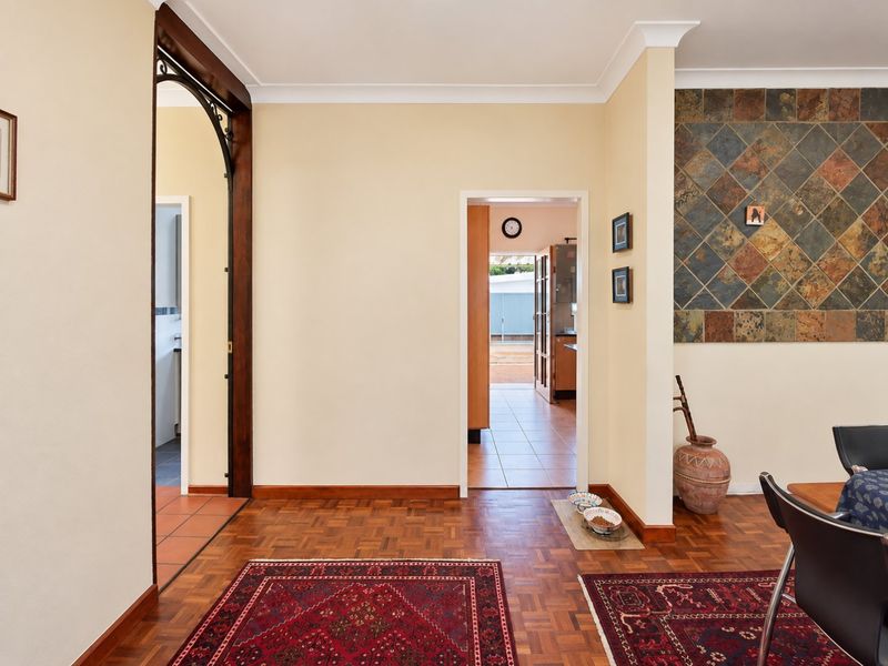 A hallway featuring parquet flooring, a decorative slate tile feature wall, and an arched doorway leading to adjacent living spaces.