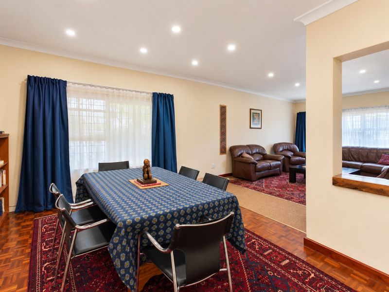 Spacious open-plan living and dining area featuring warm parquet flooring, recessed downlighting, and a convenient pass-through window connecting the spaces.