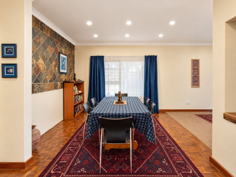 A well-maintained dining room featuring parquet flooring, a distinctive slate tile feature wall, and recessed downlighting, creating a warm and functional space.