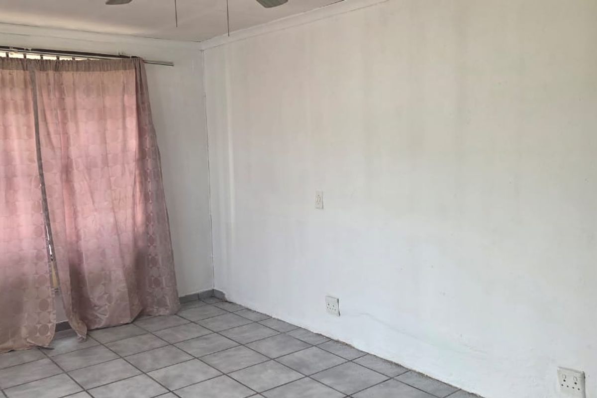An empty bedroom featuring tiled flooring, a ceiling fan, and neutral walls, providing a blank canvas for personalization.