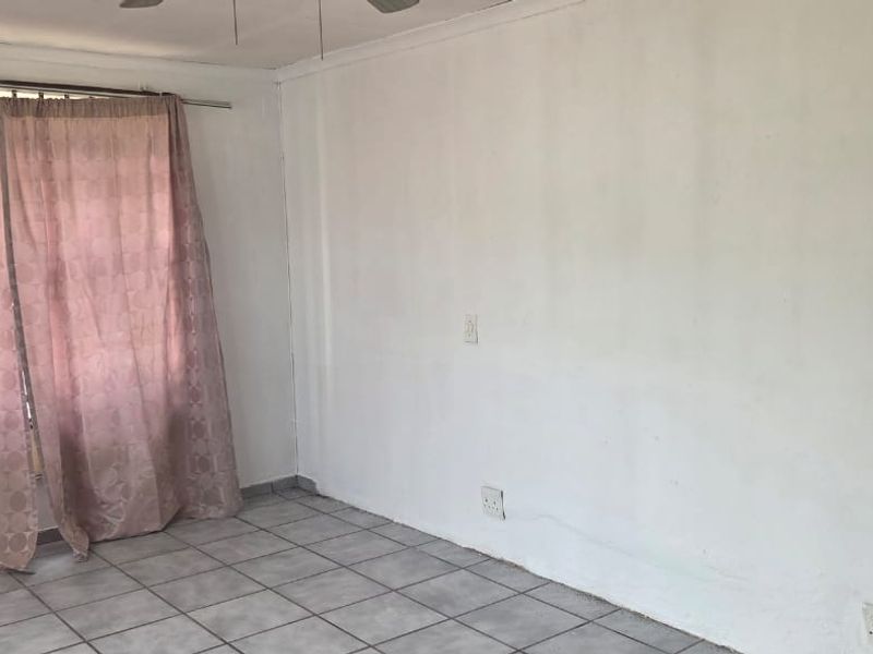 An empty bedroom featuring tiled flooring, a ceiling fan, and neutral walls, providing a blank canvas for personalization.