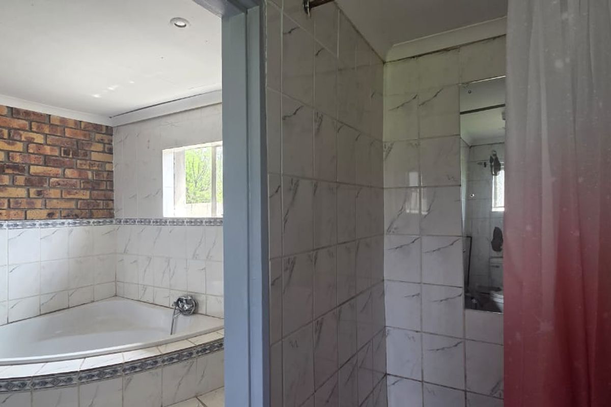 Bathroom featuring a built-in bathtub, tiled walls, and a separate shower area with an exposed brick accent wall.
