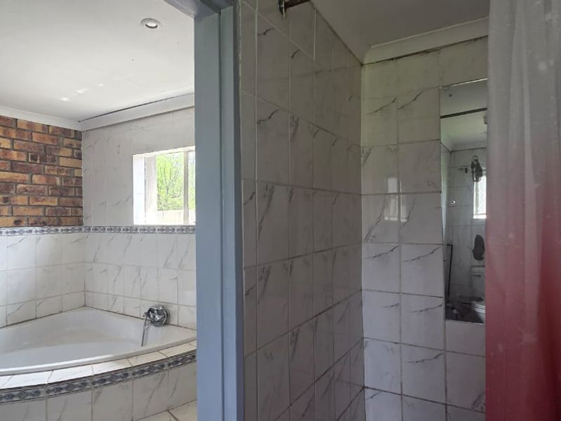 Bathroom featuring a built-in bathtub, tiled walls, and a separate shower area with an exposed brick accent wall.