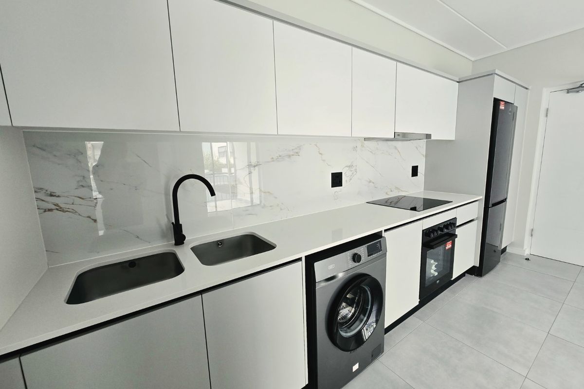 Modern kitchen featuring sleek white cabinetry, marble-look splashback, quartz countertops, integrated appliances, and high-quality finishes throughout.