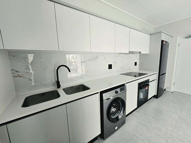 Modern kitchen featuring sleek white cabinetry, marble-look splashback, quartz countertops, integrated appliances, and high-quality finishes throughout.