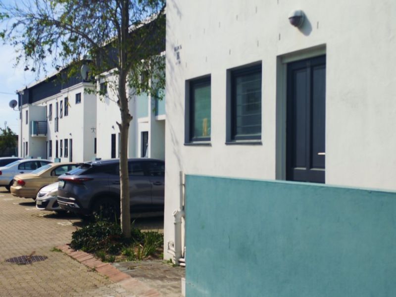 Exterior view of an apartment building facade featuring paved driveway access, modern window fixtures, and a private entrance.