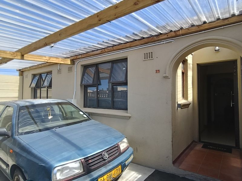 Front entrance area featuring a covered carport with a corrugated roof, arched doorway, and tiled porch entry.