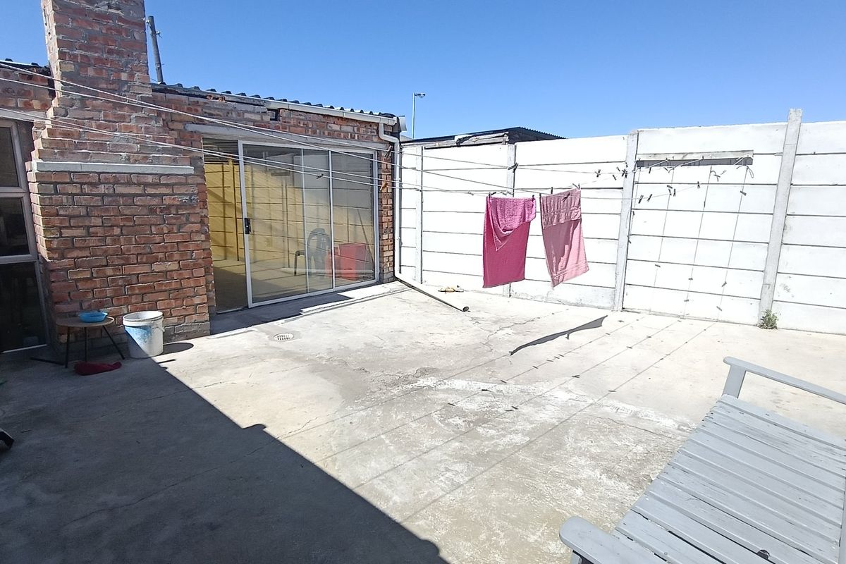 Rear exterior area featuring a concrete patio, brick chimney structure, and sliding glass door access to the main dwelling.