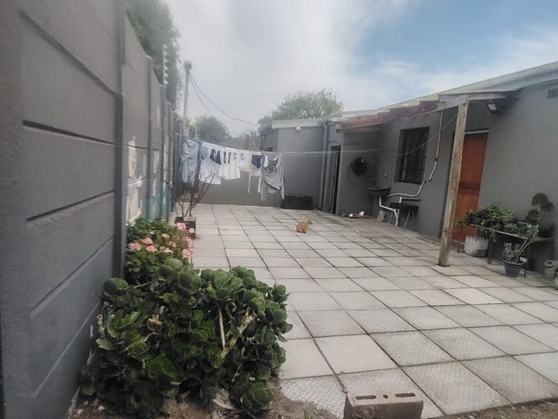 A paved rear courtyard area featuring a precast boundary wall, timber pergola structure, and direct access to the main dwelling.