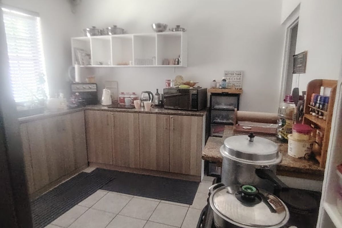 A functional kitchen featuring laminate cabinetry, granite countertops, and ceramic floor tiling with open shelving for storage.